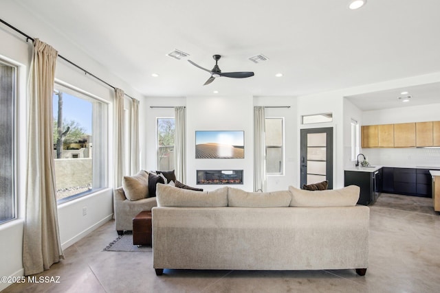 living area featuring recessed lighting, visible vents, and a glass covered fireplace