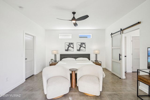 bedroom with a barn door, concrete floors, and baseboards