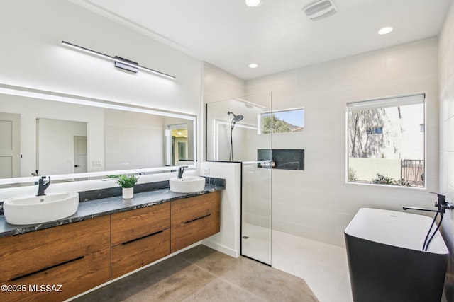 full bathroom featuring double vanity, visible vents, a walk in shower, and a sink