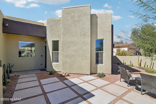 back of house with a patio area, fence, and stucco siding