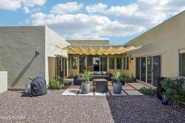 rear view of property featuring stucco siding, a patio area, and an outdoor hangout area