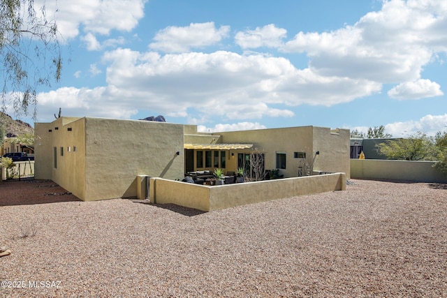 rear view of property with a patio area, fence, and stucco siding