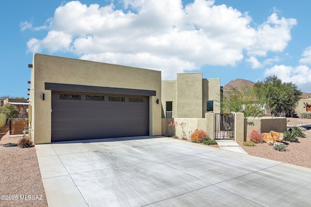 southwest-style home with driveway, an attached garage, a gate, and stucco siding