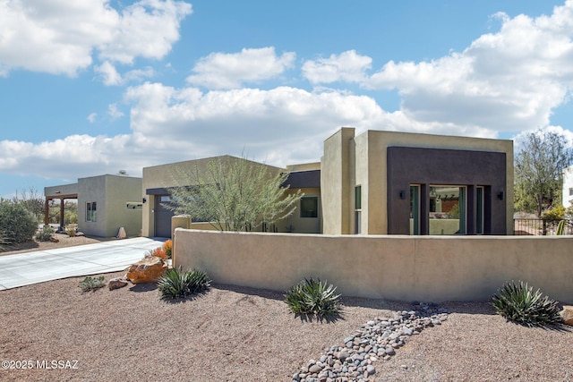 view of side of home with a fenced front yard, driveway, and stucco siding