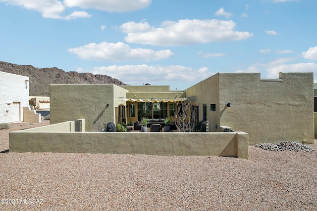 back of property featuring a patio area, a mountain view, and stucco siding