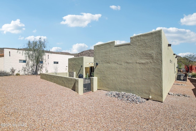 view of side of home featuring fence and stucco siding