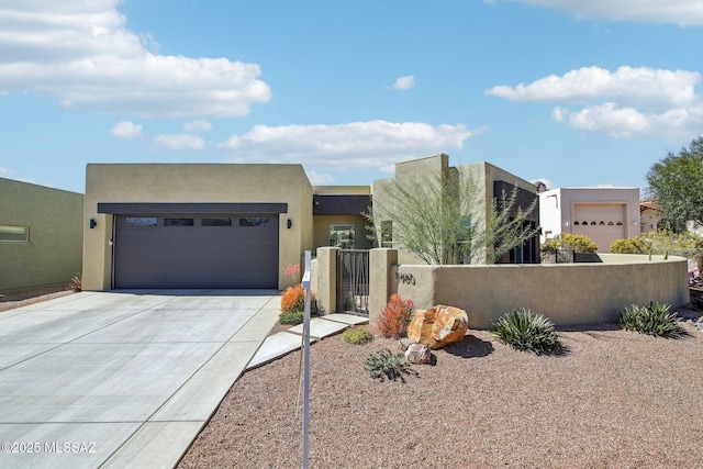 southwest-style home with a garage, driveway, a fenced front yard, and stucco siding