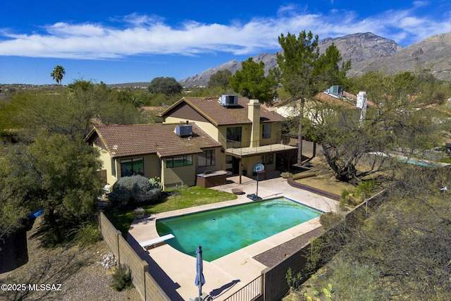 outdoor pool with central AC unit, a fenced backyard, a mountain view, and a patio