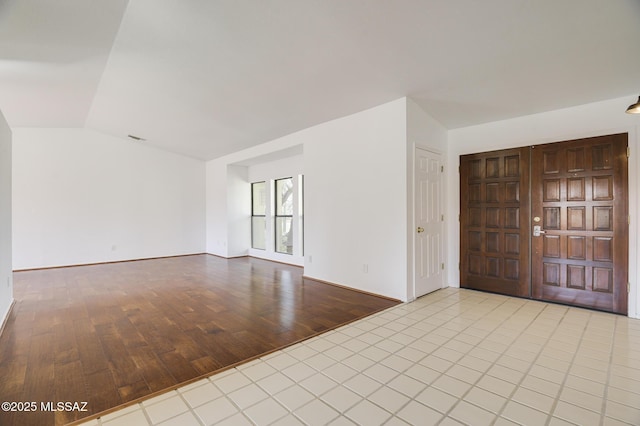 foyer entrance with lofted ceiling, visible vents, and light wood-style flooring