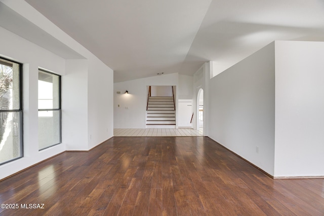 spare room featuring dark wood-style floors, stairway, and vaulted ceiling