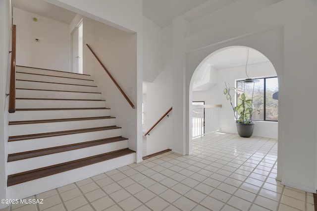 stairway with tile patterned flooring and arched walkways