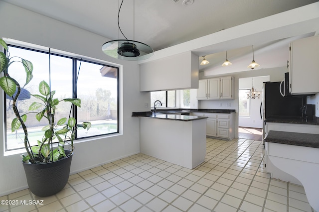 kitchen featuring dark countertops, light tile patterned floors, white cabinets, and a sink