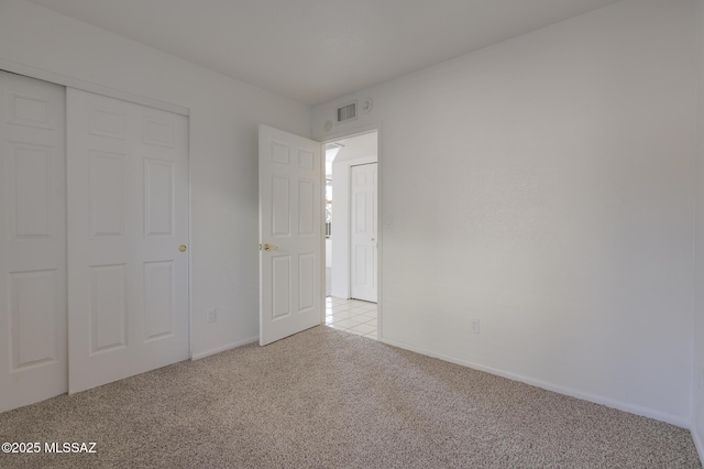 unfurnished bedroom featuring a closet, light carpet, and baseboards