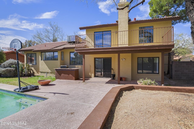 back of house with a balcony, a patio area, and stucco siding