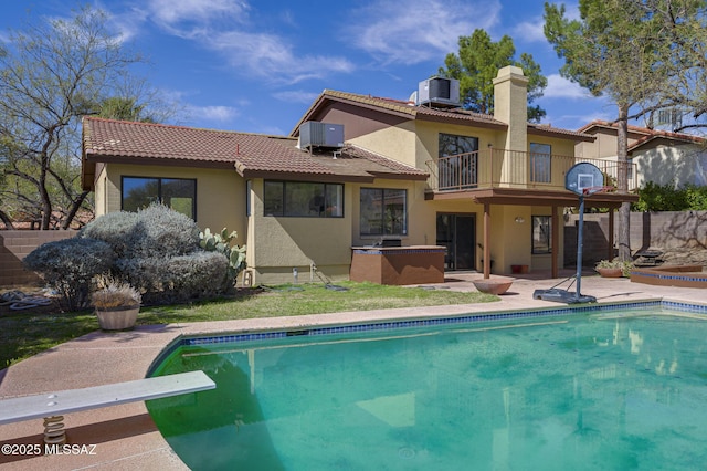 back of property featuring a tiled roof, stucco siding, a balcony, and central AC unit