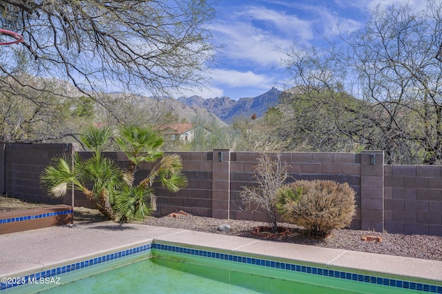 view of swimming pool featuring a fenced backyard, a mountain view, and a pool