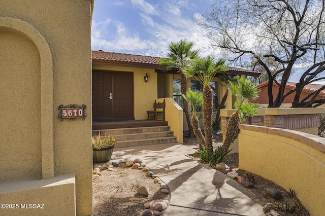 entrance to property featuring a tiled roof and stucco siding