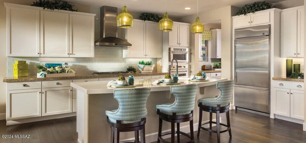 kitchen with white cabinetry, appliances with stainless steel finishes, extractor fan, and pendant lighting