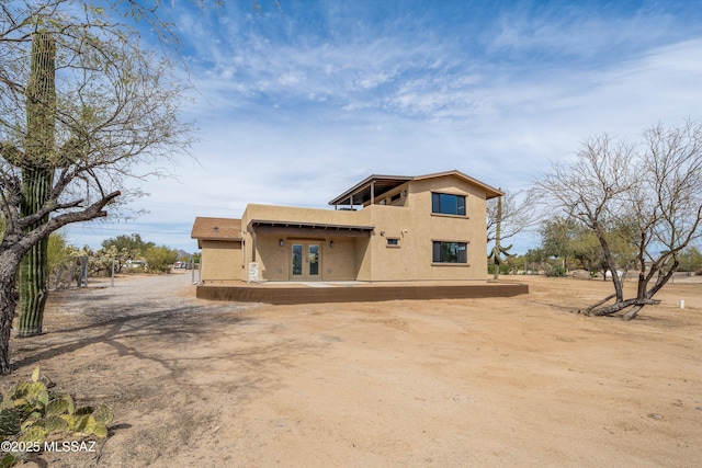 rear view of property with stucco siding and french doors