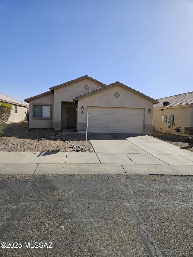 view of front of home with driveway, an attached garage, a tile roof, and stucco siding