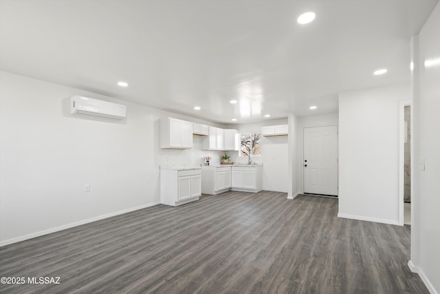 kitchen featuring white cabinets, dark wood-style floors, an AC wall unit, a sink, and recessed lighting