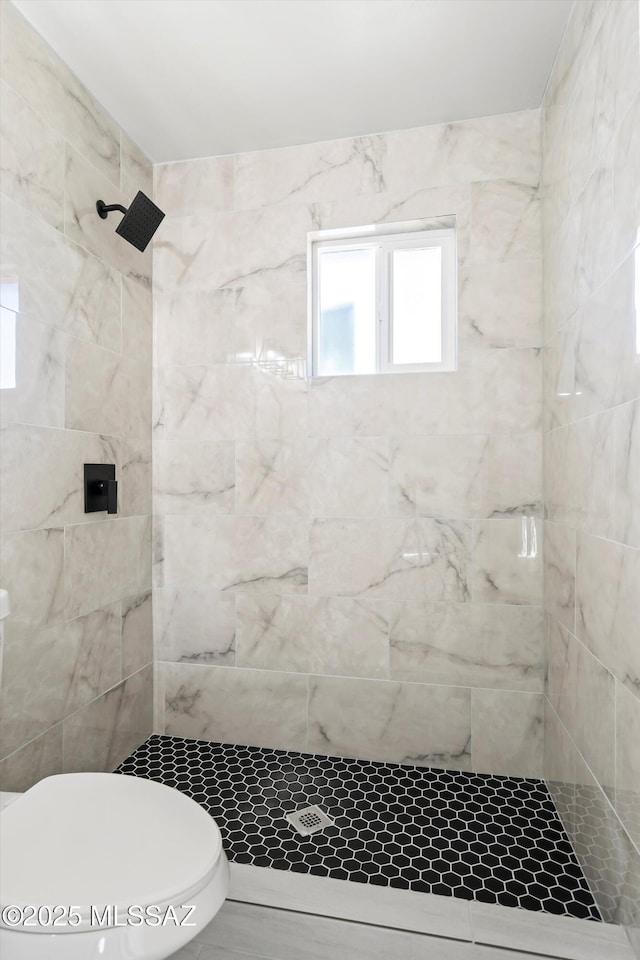 bathroom featuring a tile shower and toilet