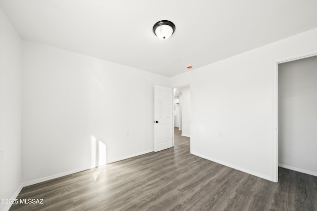 unfurnished bedroom with dark wood-style flooring and baseboards