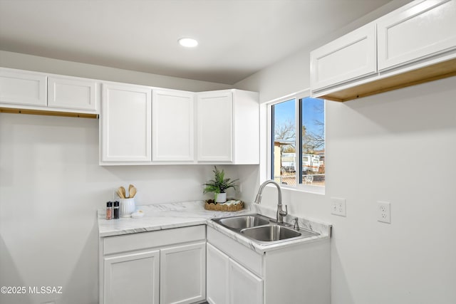 kitchen with light countertops, a sink, white cabinetry, and recessed lighting