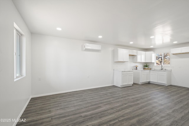 kitchen featuring a wall unit AC, recessed lighting, dark wood-style flooring, baseboards, and white cabinets