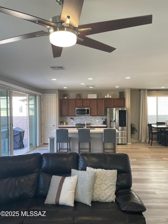 living area with ceiling fan, visible vents, light wood-style flooring, and recessed lighting