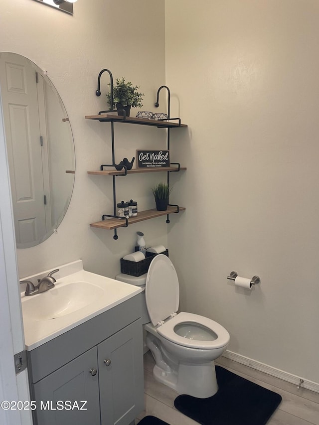 bathroom with baseboards, vanity, toilet, and wood finished floors