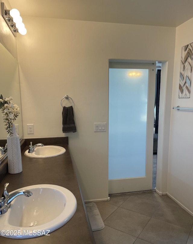 bathroom featuring baseboards, a sink, and tile patterned floors