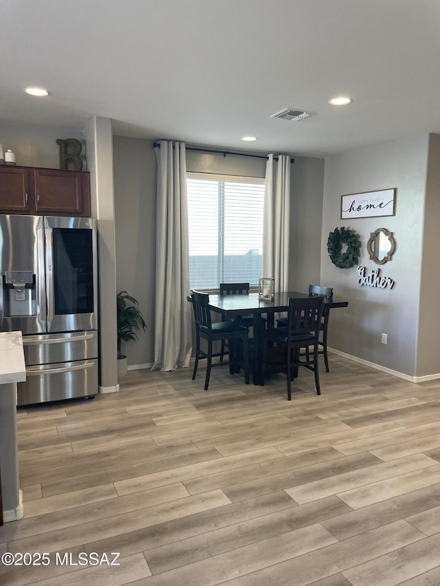 dining space featuring light wood-style flooring, visible vents, and baseboards