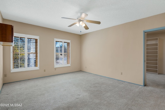 carpeted spare room featuring a ceiling fan and a textured ceiling