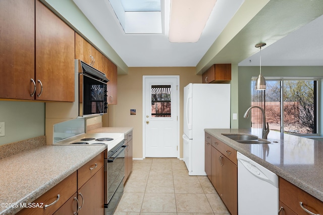 kitchen featuring a sink, plenty of natural light, white appliances, light tile patterned flooring, and brown cabinetry