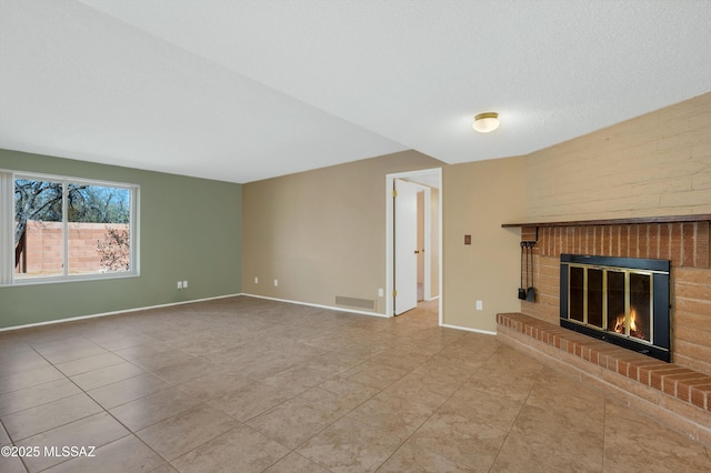 unfurnished living room featuring visible vents, a brick fireplace, baseboards, tile patterned floors, and a textured ceiling