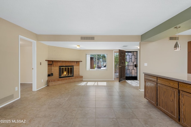 unfurnished living room with a brick fireplace, light tile patterned floors, baseboards, and visible vents