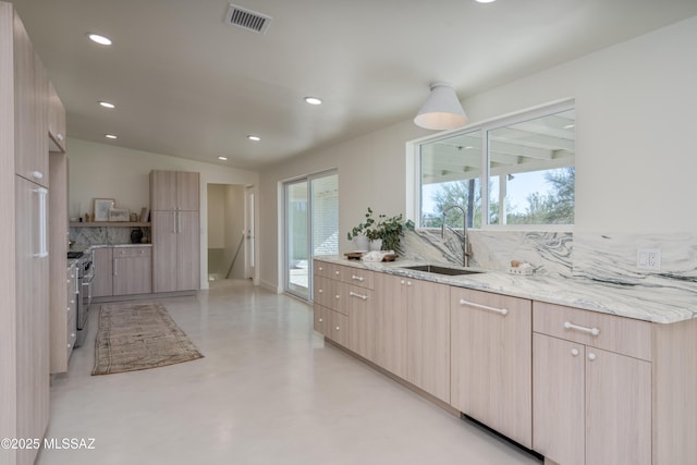 kitchen featuring high end stove, modern cabinets, a sink, and visible vents