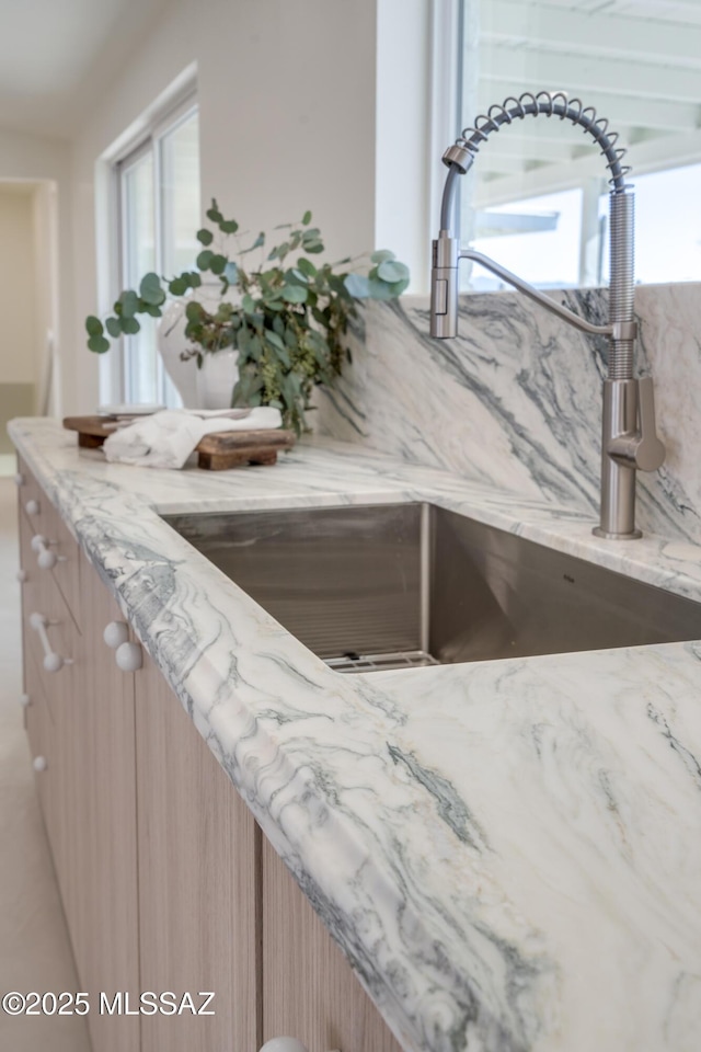 room details with light stone counters, light brown cabinets, and a sink