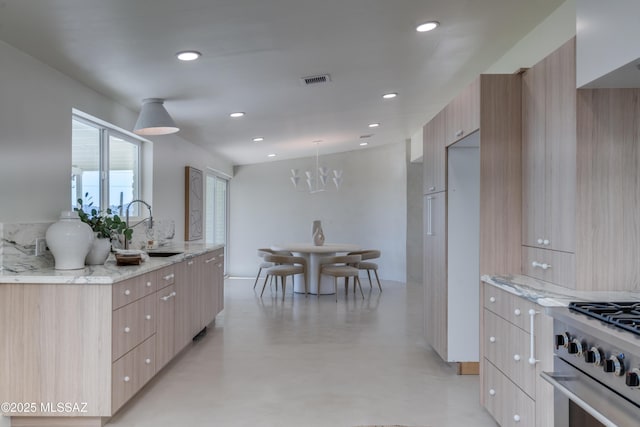 kitchen featuring light stone counters, light brown cabinets, a sink, and modern cabinets