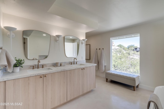 full bath with finished concrete floors, a sink, baseboards, and double vanity