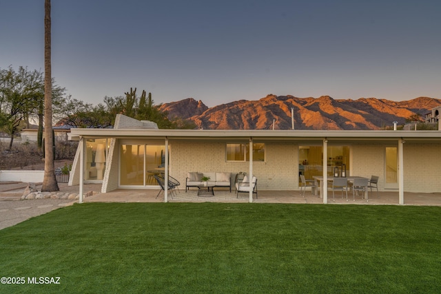 back of house featuring brick siding, a lawn, a patio area, and an outdoor living space