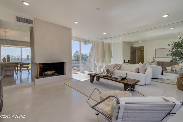 living area with a wealth of natural light, a fireplace, visible vents, and finished concrete floors