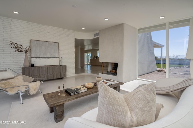 living area featuring visible vents, brick wall, expansive windows, a multi sided fireplace, and recessed lighting