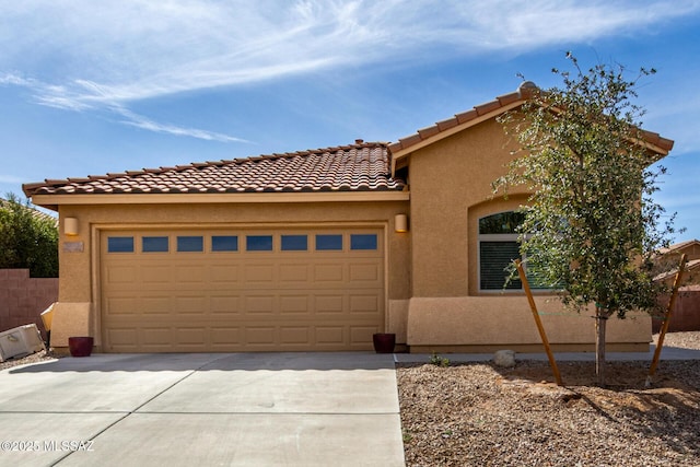 view of front of house featuring stucco siding, concrete driveway, an attached garage, fence, and a tiled roof