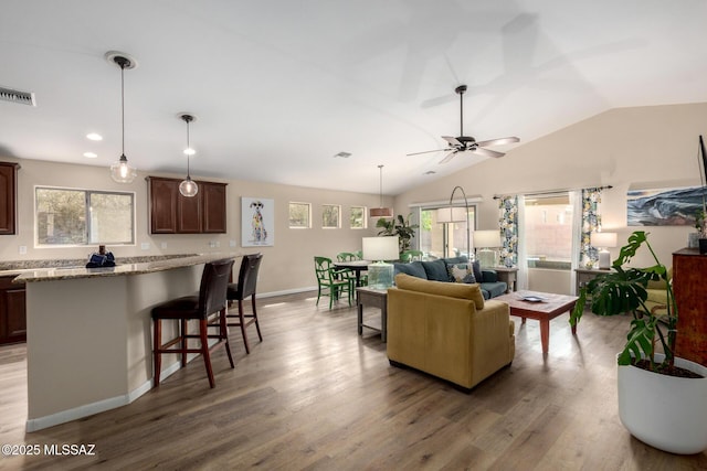 living room featuring vaulted ceiling, wood finished floors, visible vents, and a ceiling fan