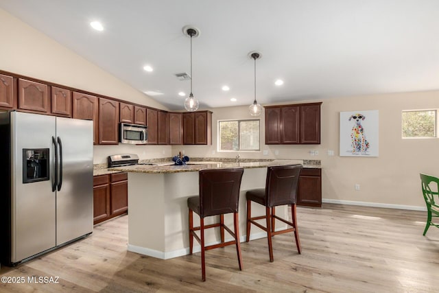 kitchen with a breakfast bar area, stainless steel appliances, visible vents, light wood-style floors, and vaulted ceiling