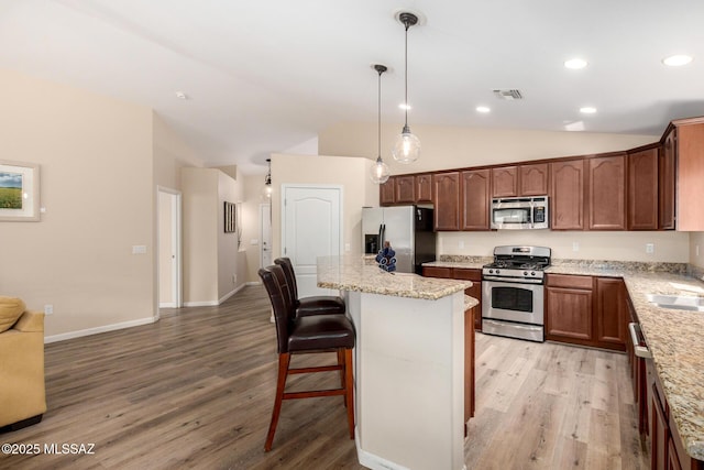 kitchen with appliances with stainless steel finishes, light wood-type flooring, visible vents, and vaulted ceiling