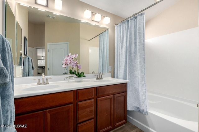 full bathroom featuring double vanity, shower / bath combo, visible vents, and a sink