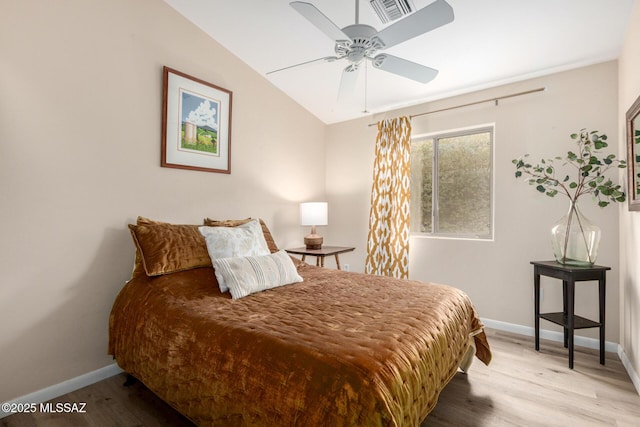 bedroom featuring lofted ceiling, visible vents, baseboards, and wood finished floors